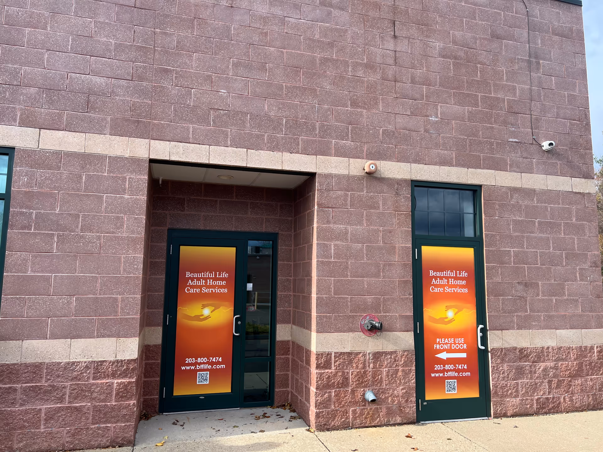 Brick exterior of a facility with two doors displaying Beautiful Life Adult Home Care Services.