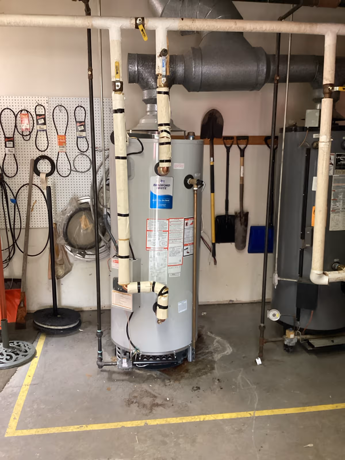 Industrial utility room at Eden Heights, featuring a water heater, pipes, and assorted tools.