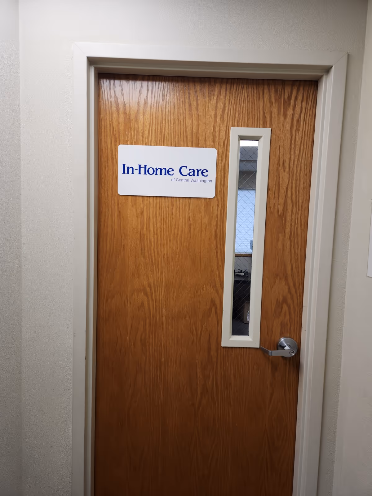 Wooden interior door with a sign reading In-Home Care and a narrow vertical window.