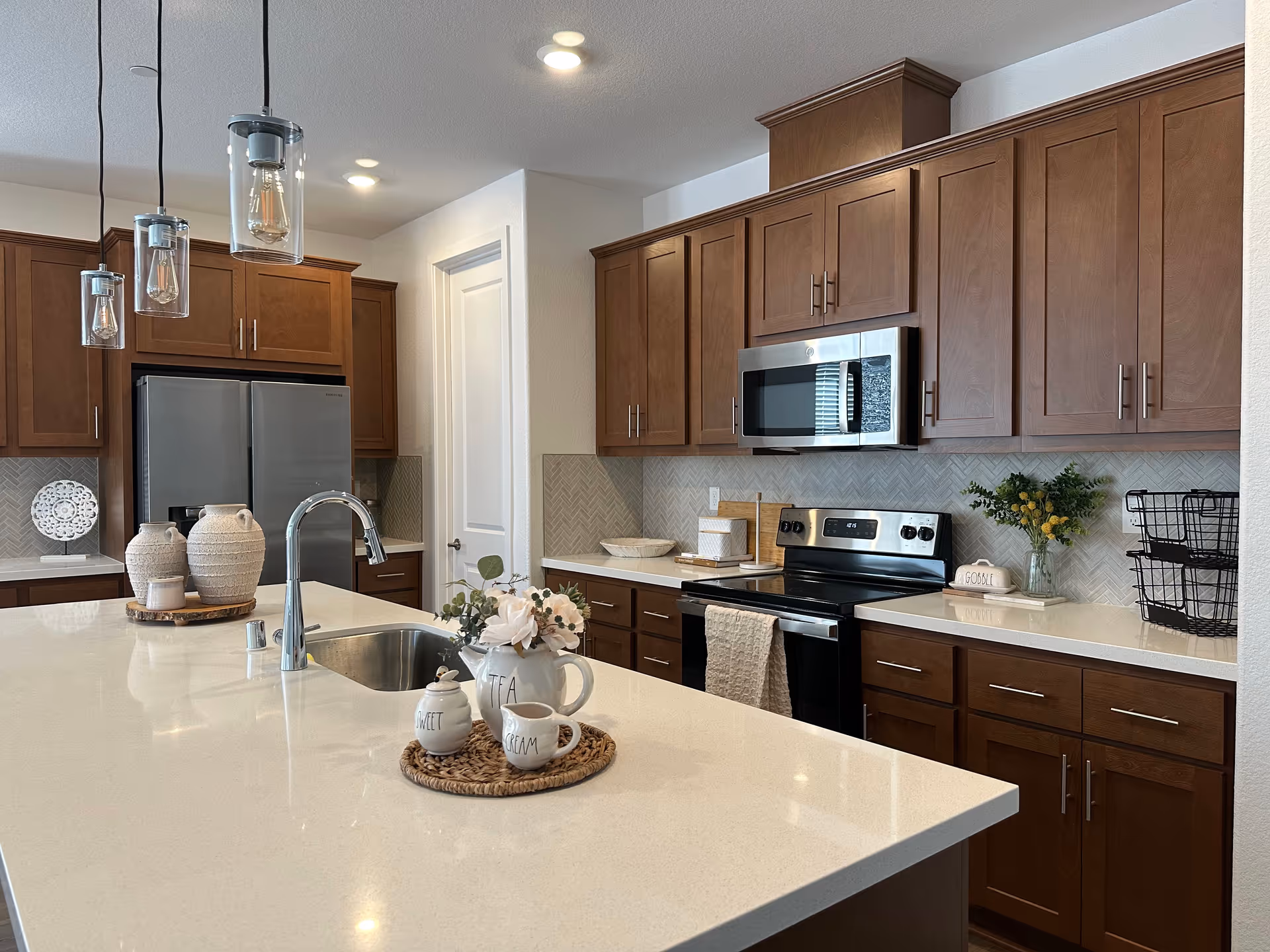 Modern kitchen with brown cabinets, stainless appliances, and an island with a sink.