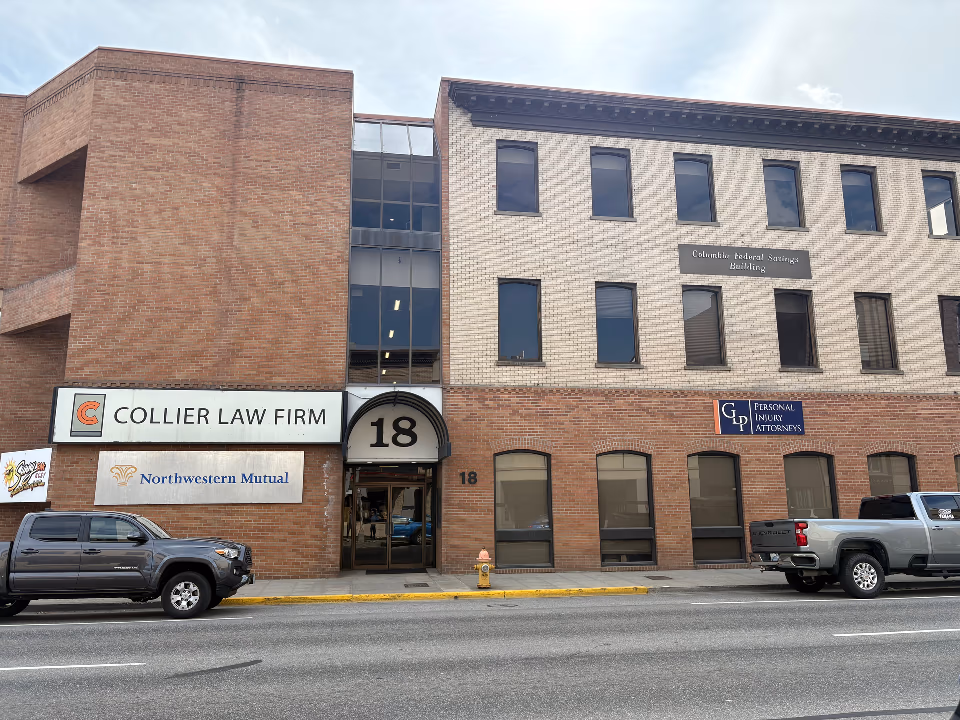 Exterior view of a brick building with storefront signs including Collier Law Firm.