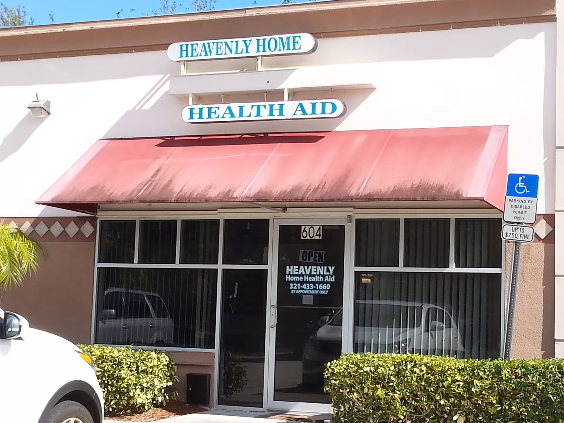 Exterior storefront for Heavenly Home Health Aid with red awning and glass doors.