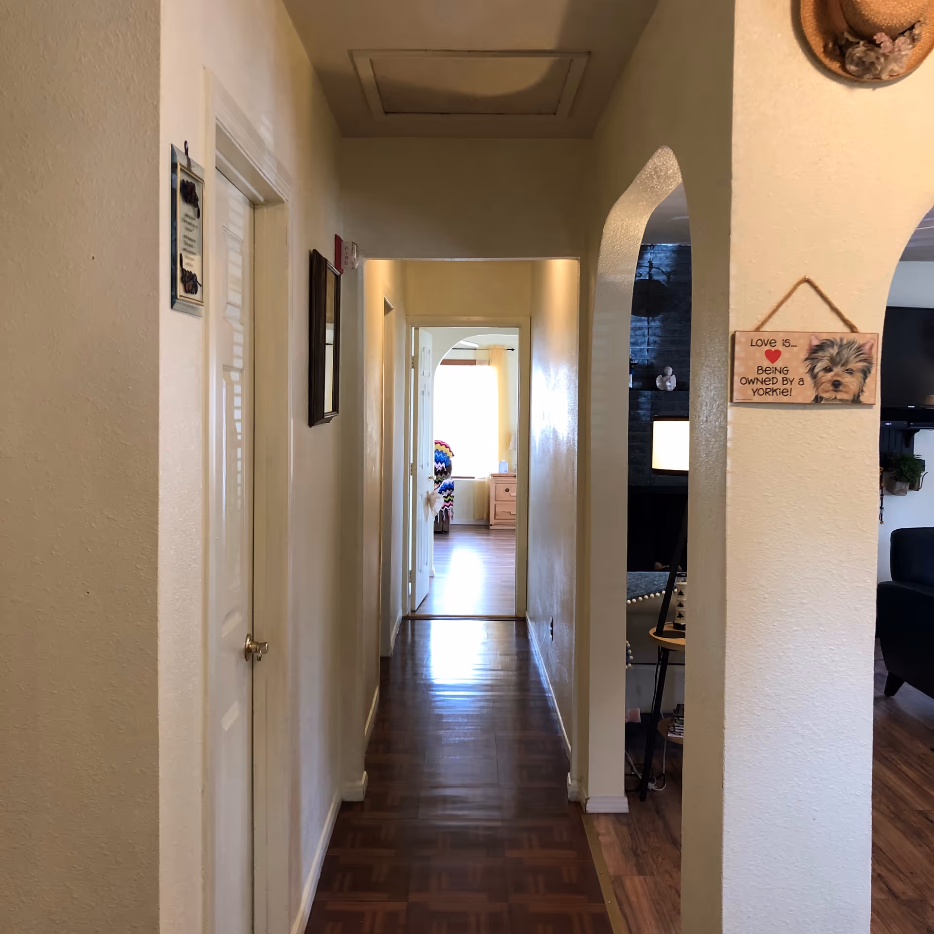 Long hallway in a senior living facility with doors, arches, and a distant bright room.
