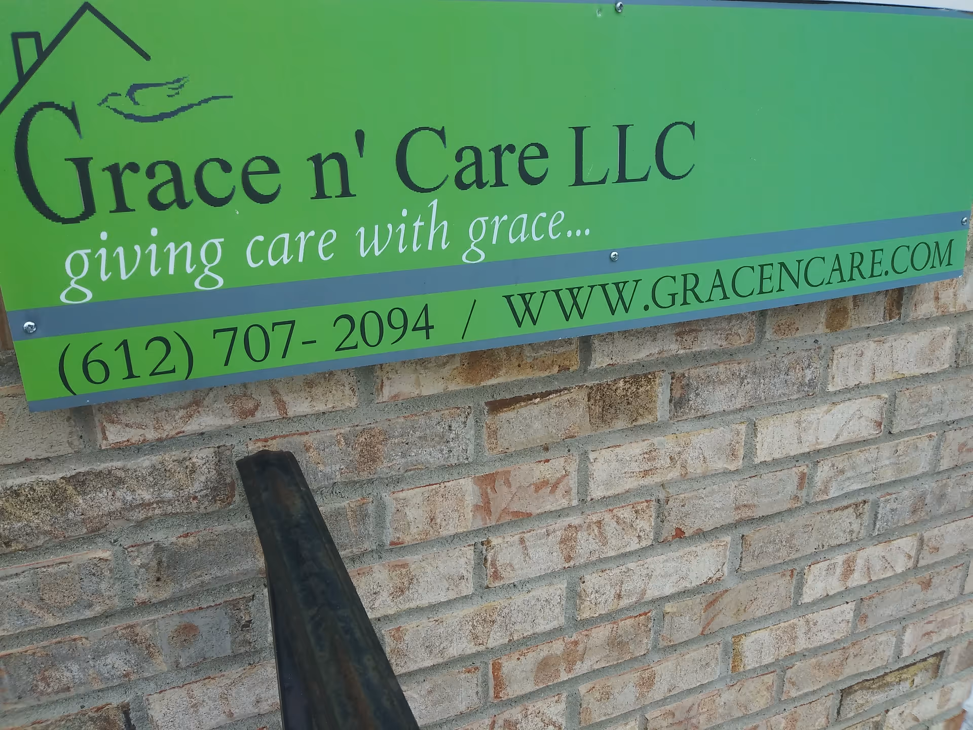 Green Grace n' Care LLC sign on brick wall with phone number