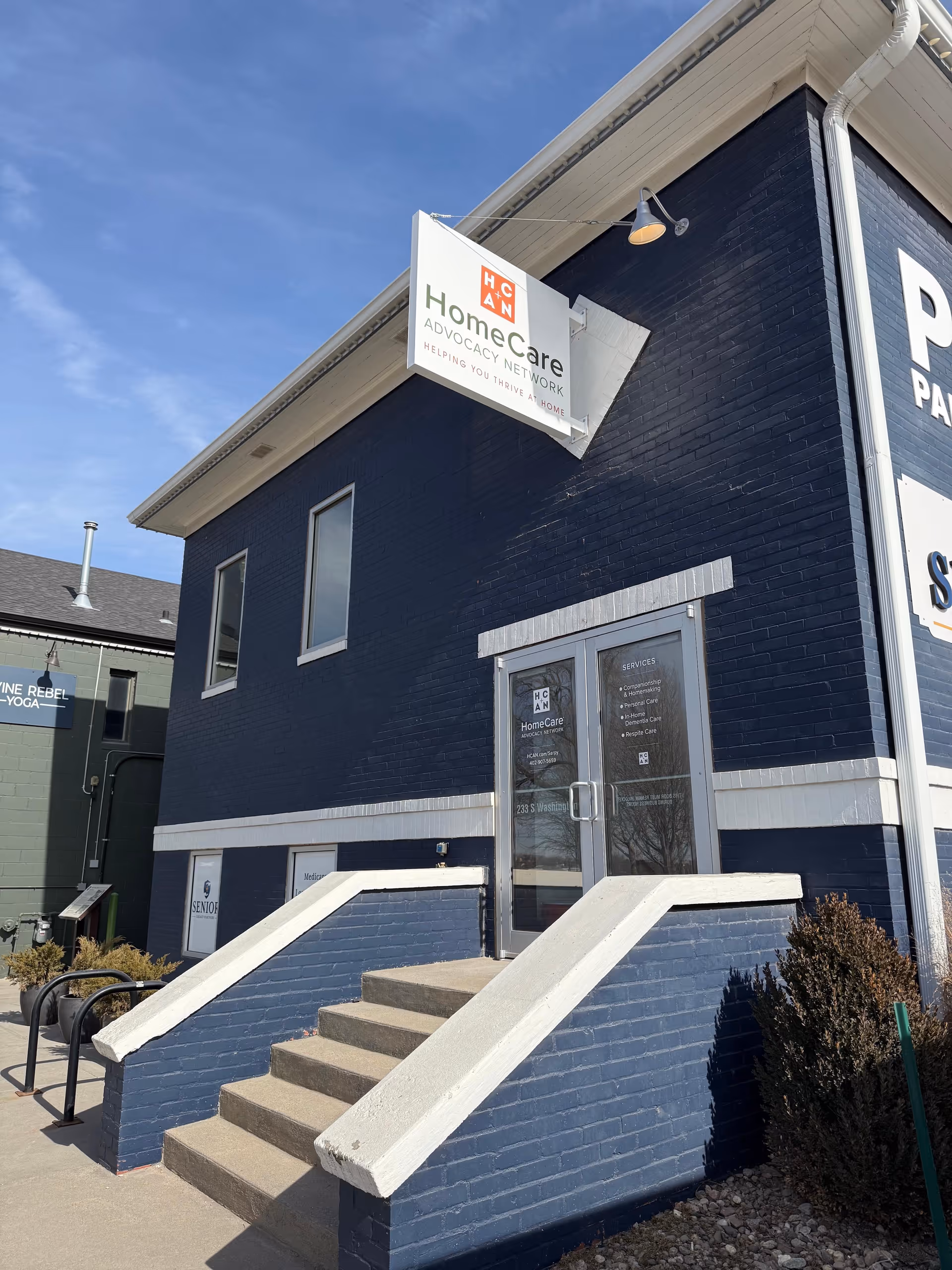 Blue brick building with HomeCare Advocacy Network sign and glass entry at steps.