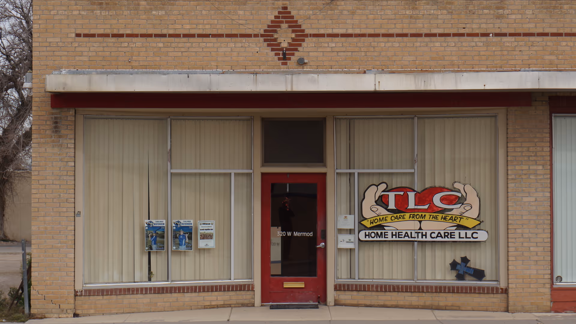 Brick storefront with TLC Home Health Care logo, large front windows, and a red entry door.