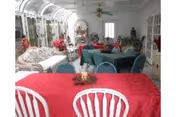 Bright dining room with red tablecloths and white chairs in a senior living facility.