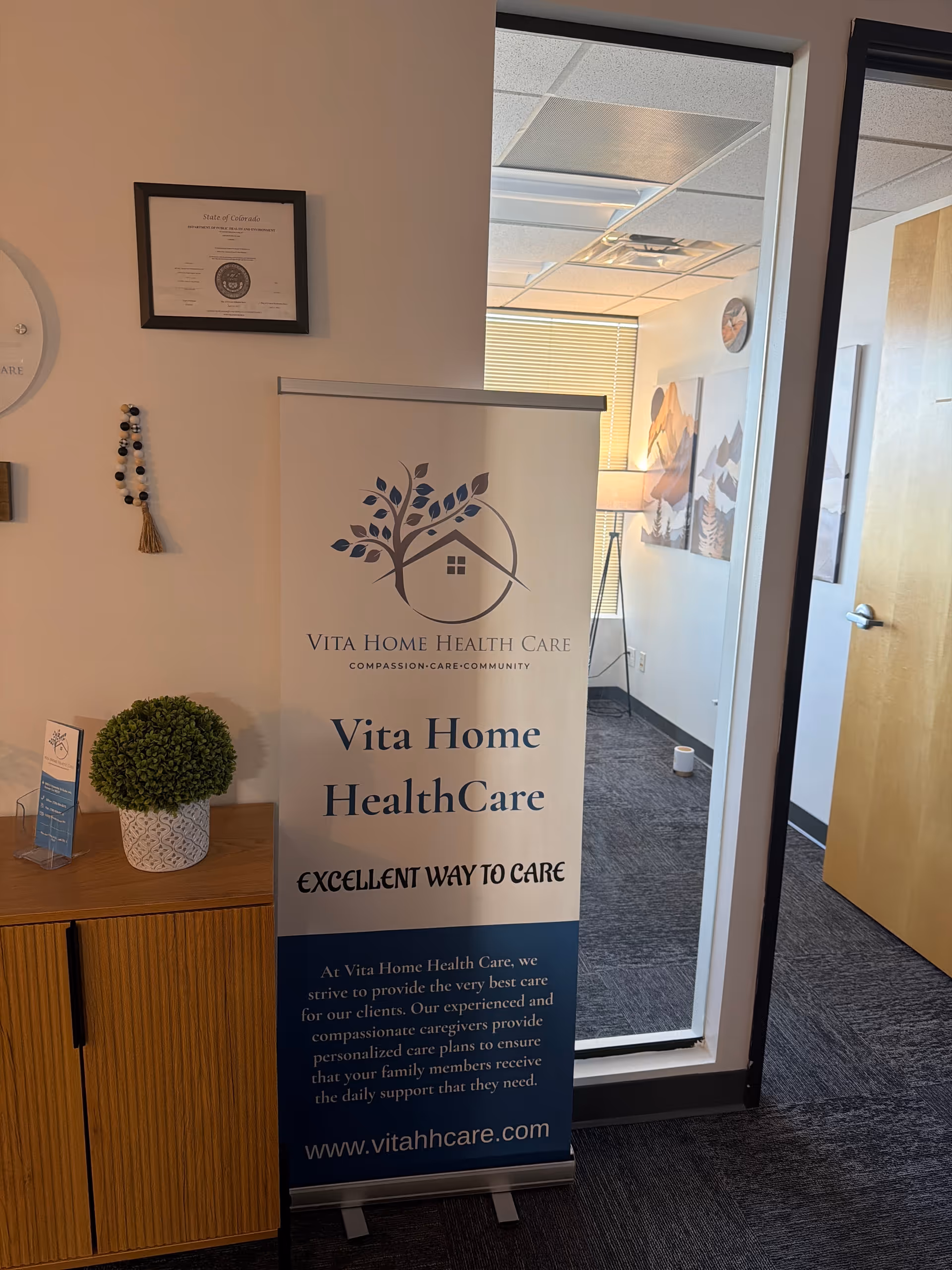 Interior reception area with a Vita Home Health Care banner beside a wooden cabinet.