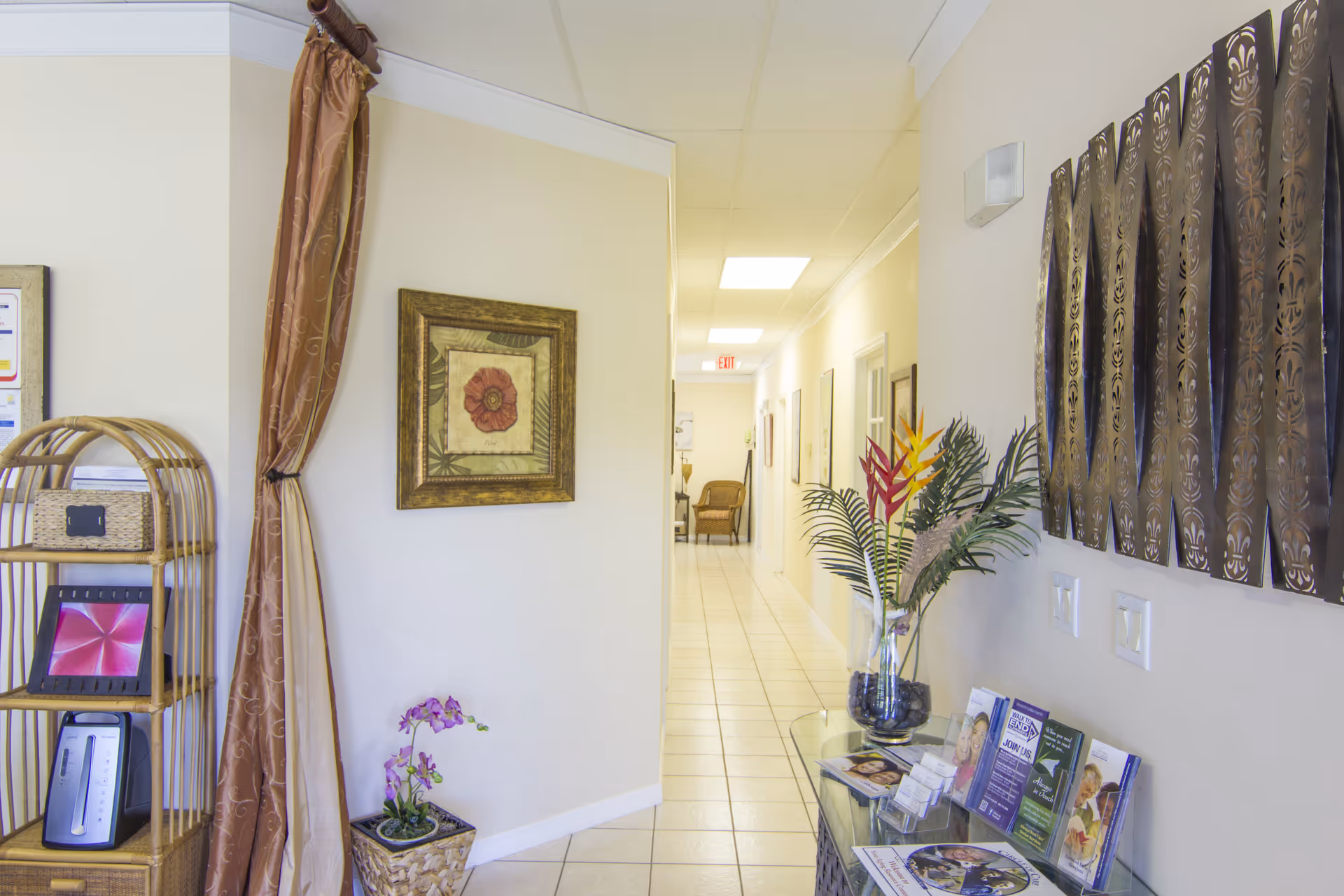 Hallway in a senior living facility with plants, art, and a brochure display.
