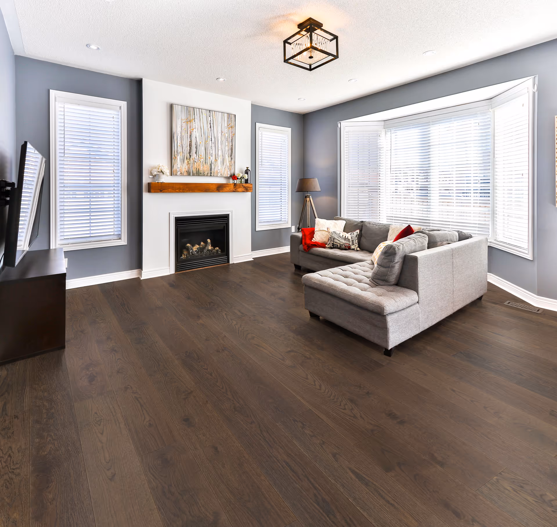 Bright living room with gray-blue walls, fireplace, and large bay windows.