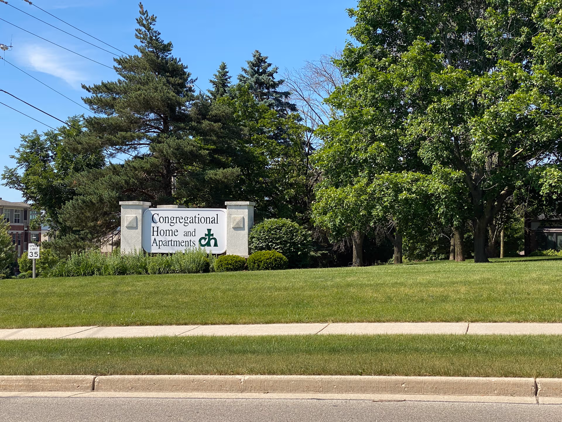 A sign reads Congregational Home and Apartments beside a grassy lawn and trees.