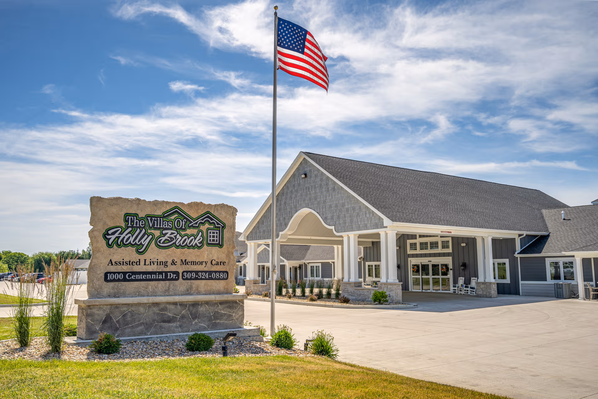 Exterior view of The Villas of Holly Brook East Peoria with flagpole and sign.