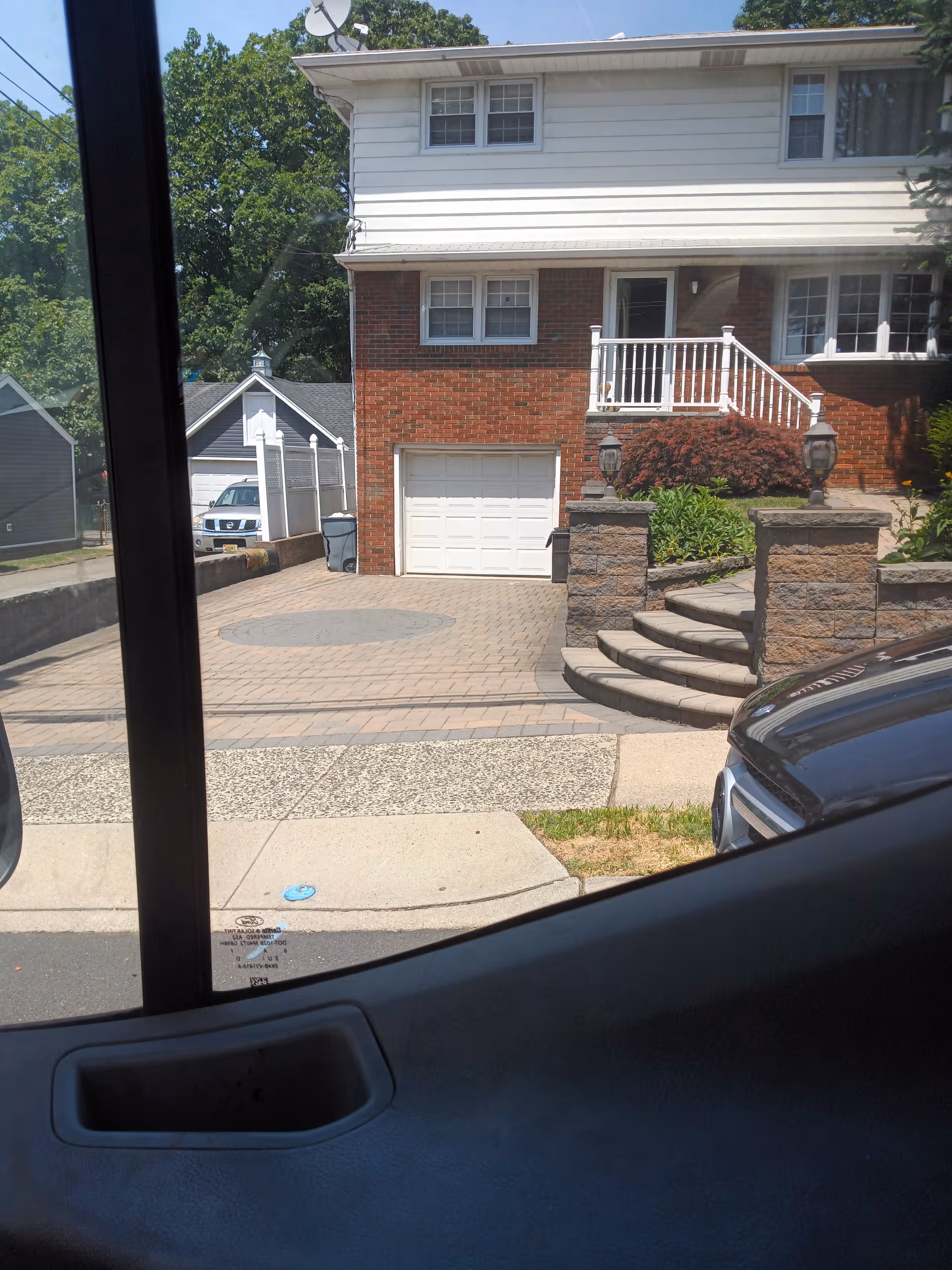 View of Miriam Apartments II exterior: brick lower level, white siding upper, stairs, and driveway.