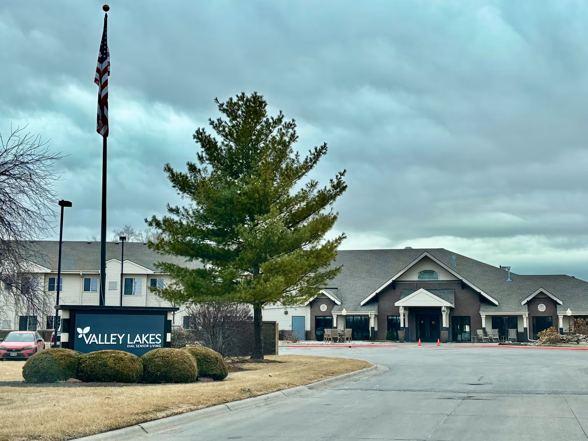 Exterior view of a senior living facility with a front entrance and sign.