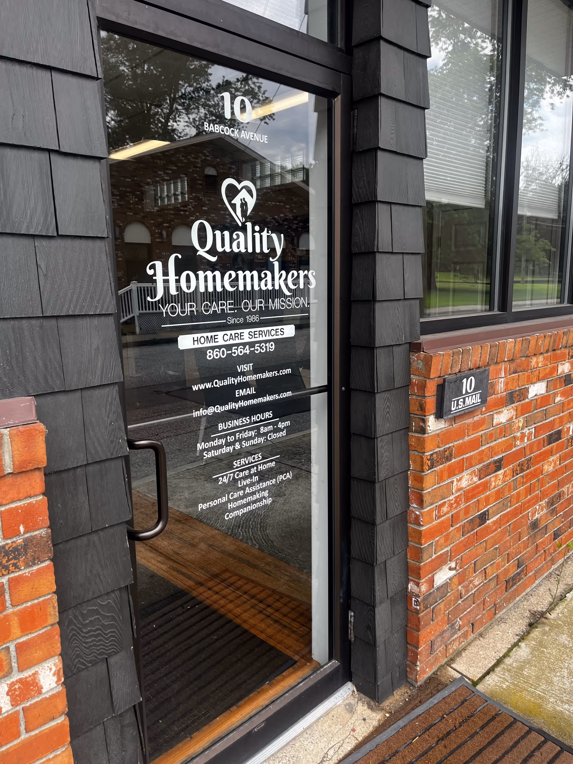 Glass door displaying Quality Homemakers sign on brick exterior entry
