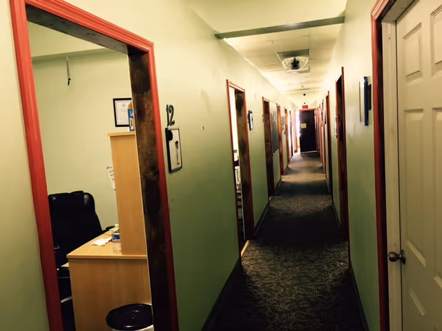Long hallway in a senior living facility with many doors and a small office.