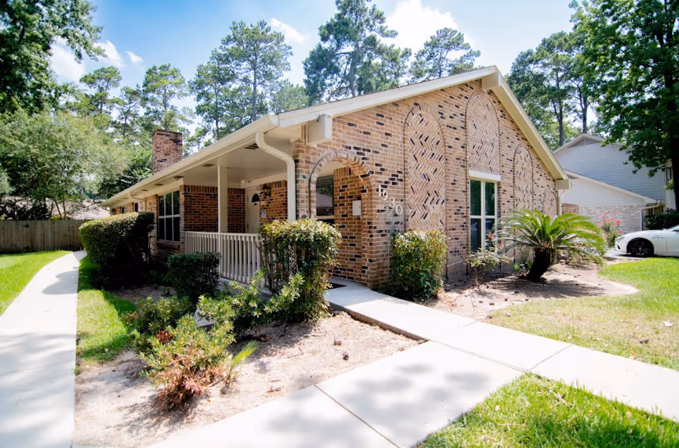Single-story brick senior living home with arched brick facade, front yard, and concrete walkway.