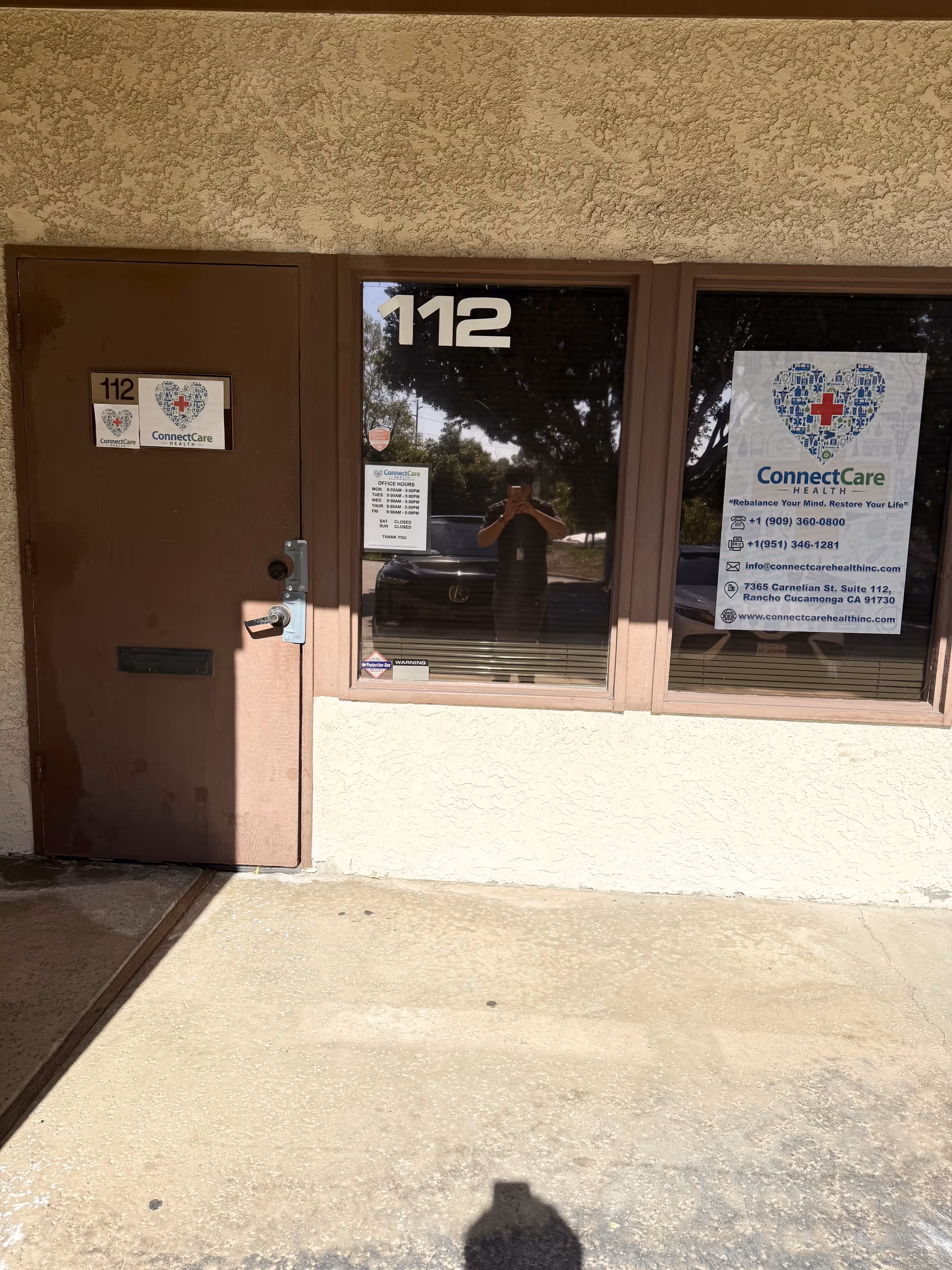 Brown door labeled 112 beside a window with ConnectCare Health signs outside