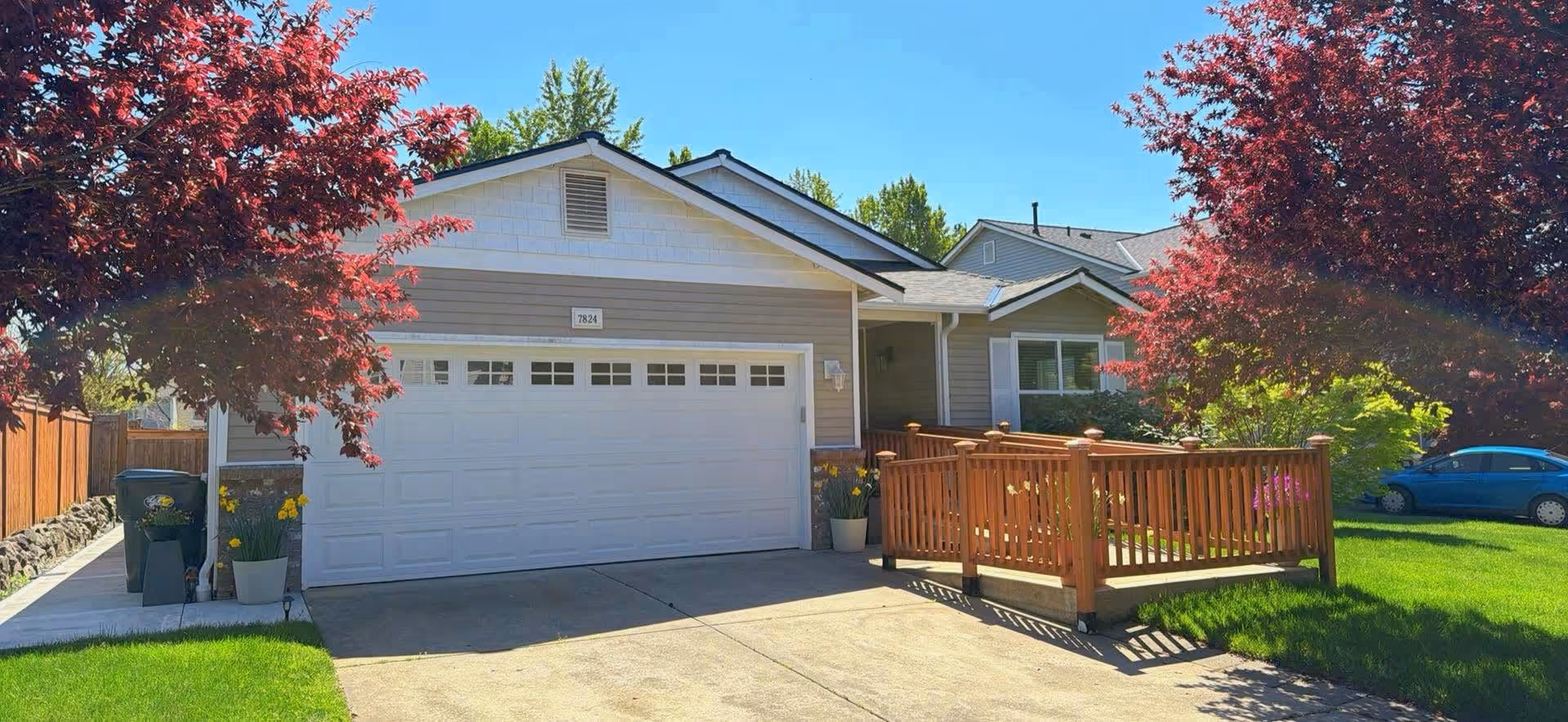 Front exterior of a single-story home with a two-car garage and wooden deck.