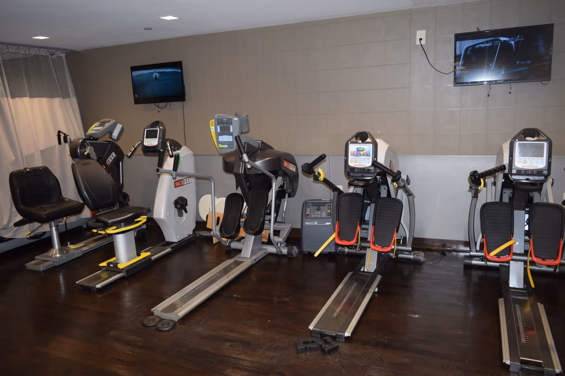 Interior fitness room with treadmills and stationary bikes in a senior living facility.