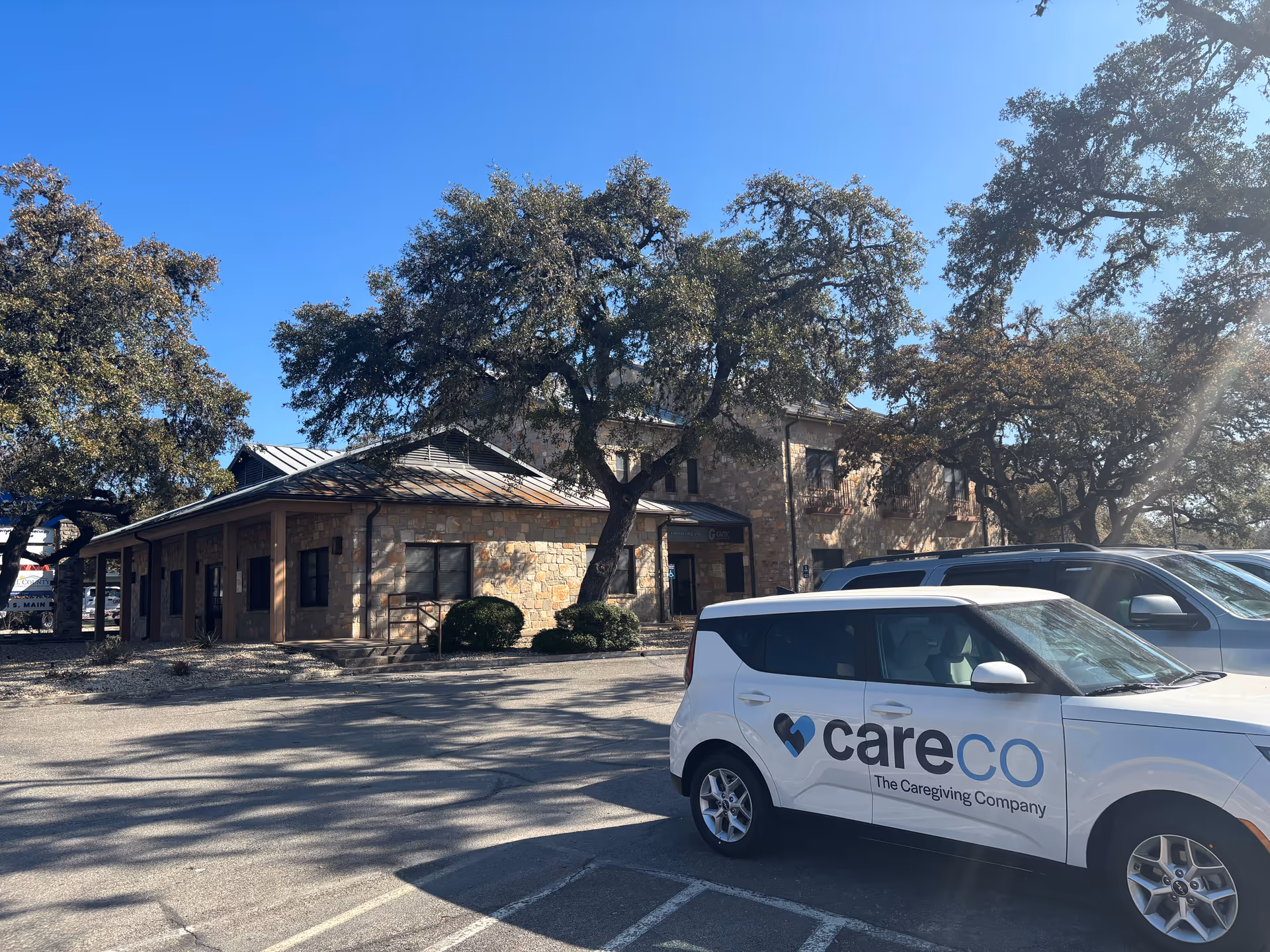 Exterior view of CareCo senior home building with a branded vehicle parked outside.