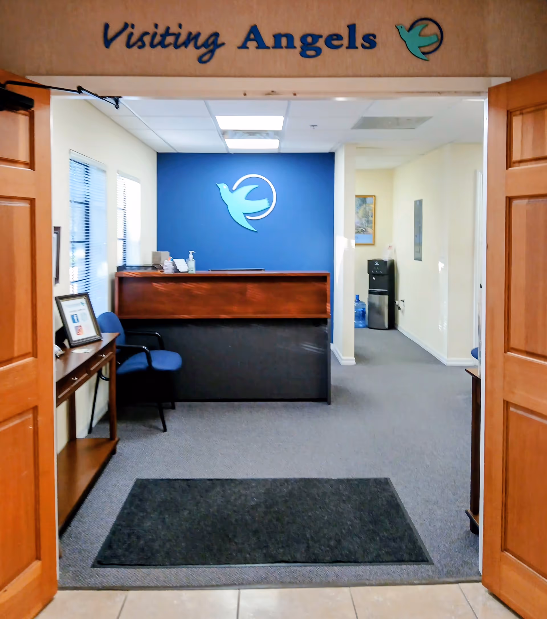 Reception area for Visiting Angels Senior Home Care with blue logo wall and front desk.