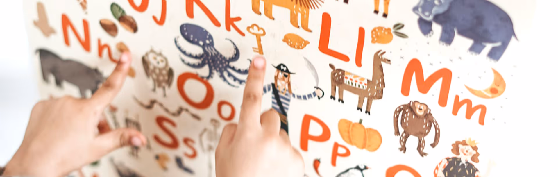 Two hands point at a colorful alphabet mural on a wall.