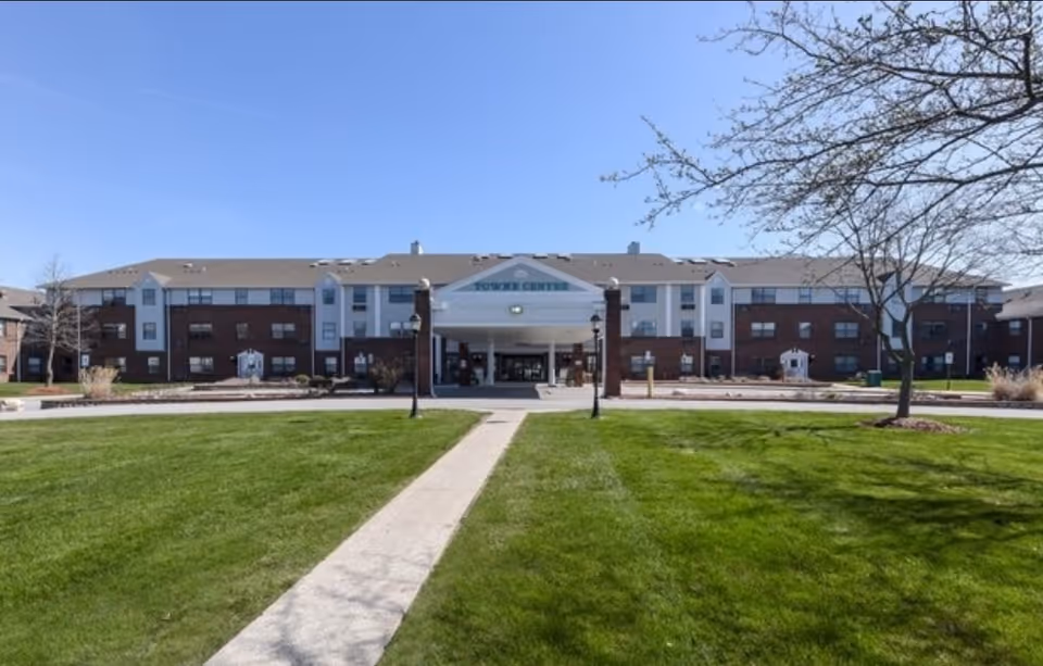 Front view of the three-story Towne Centre building with a central covered entrance, lawn, and walkway.