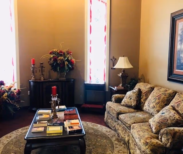 Hospice of Southern Kentucky lounge with a floral-patterned sofa, coffee table, candles, and floral arrangements.