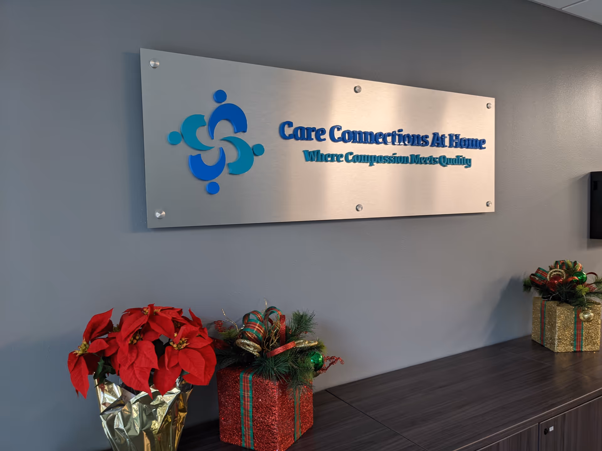 Lobby area with Care Connections At Home sign, poinsettia plants, and gift boxes.