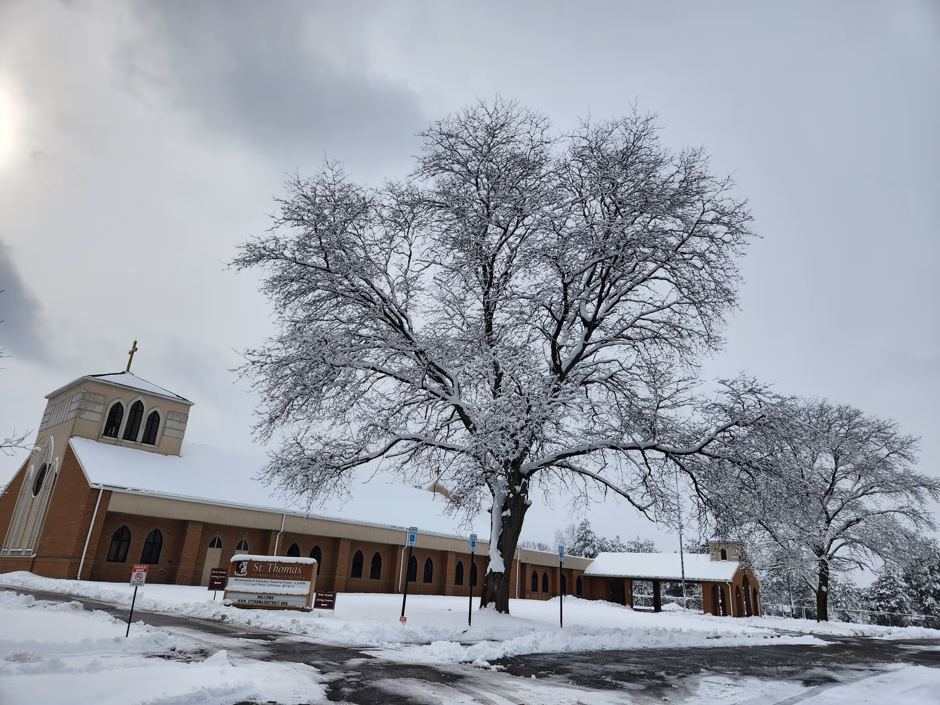 Snowy exterior of a church-like building with bare trees and overcast sky.