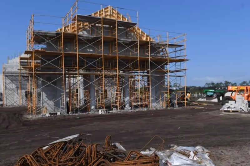 Under-construction building with yellow scaffolding on a construction site.