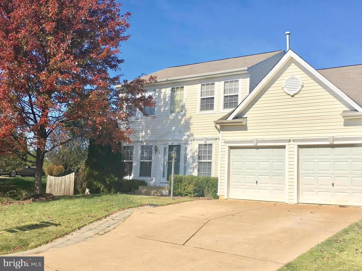 Two-story beige house with attached double garage and a spacious front driveway.