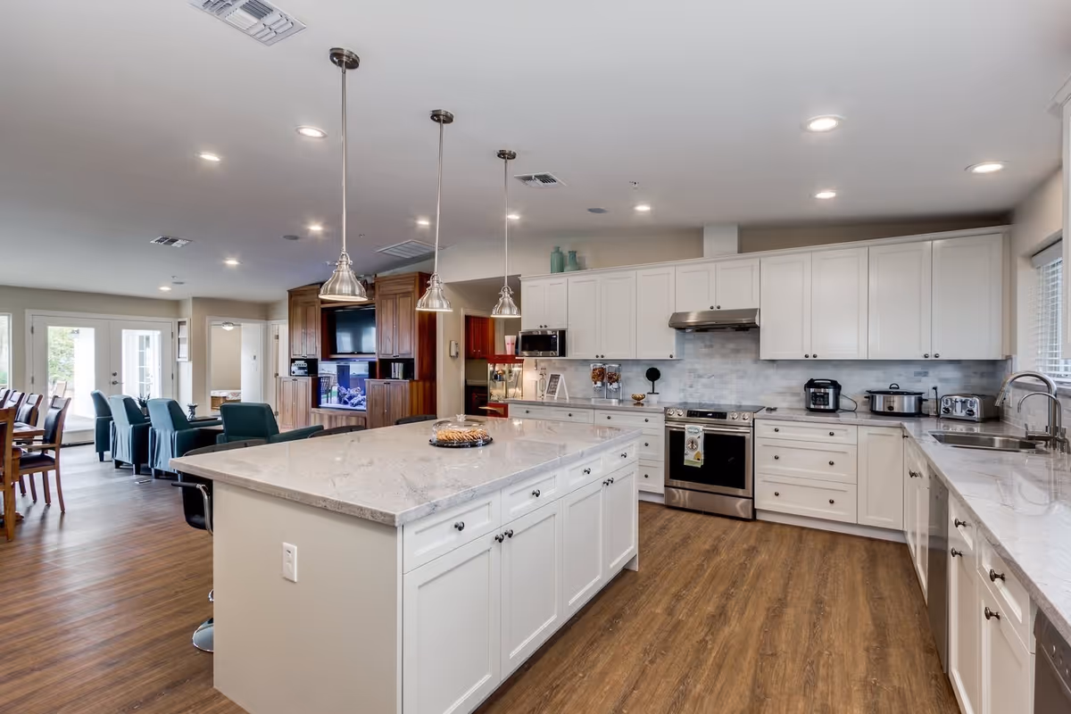 Bright, modern kitchen with white cabinets, island, and dining area visible in background.