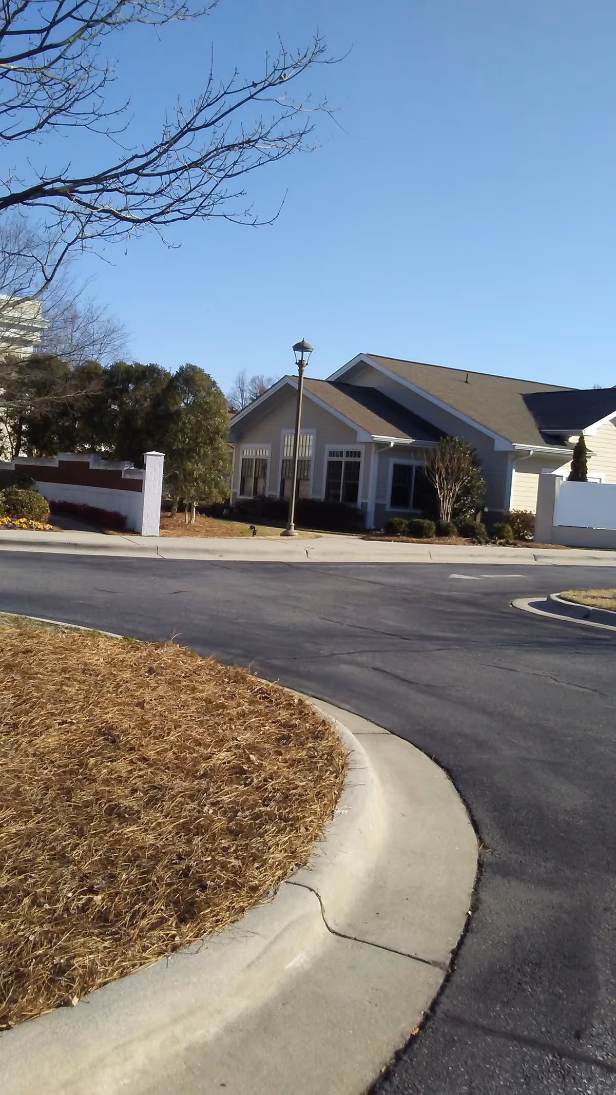 Exterior view of a single-story hospice building with a curved road and bare trees.
