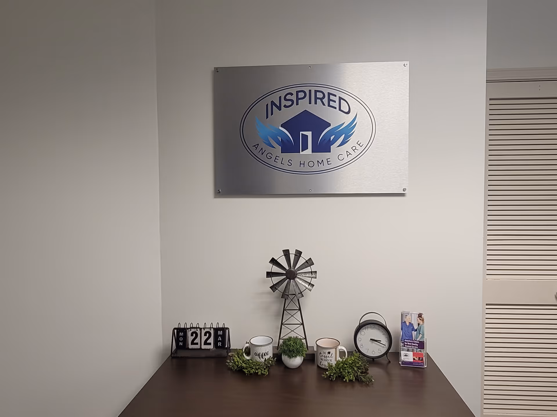 Indoor office area with a wall plaque reading Inspired Angels Home Care and desk décor.