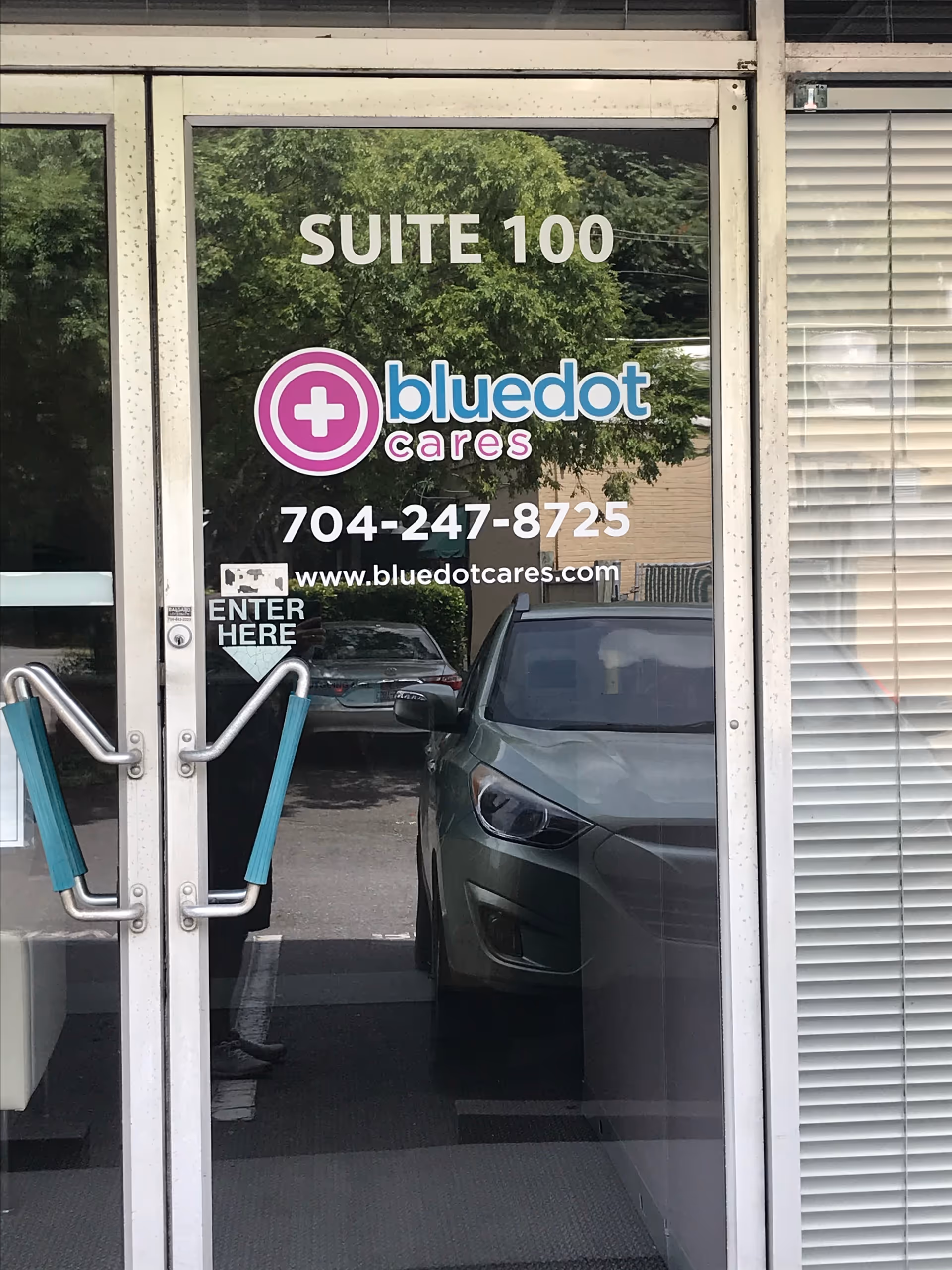 Glass entrance door with BlueDot Cares branding and Suite 100 visible