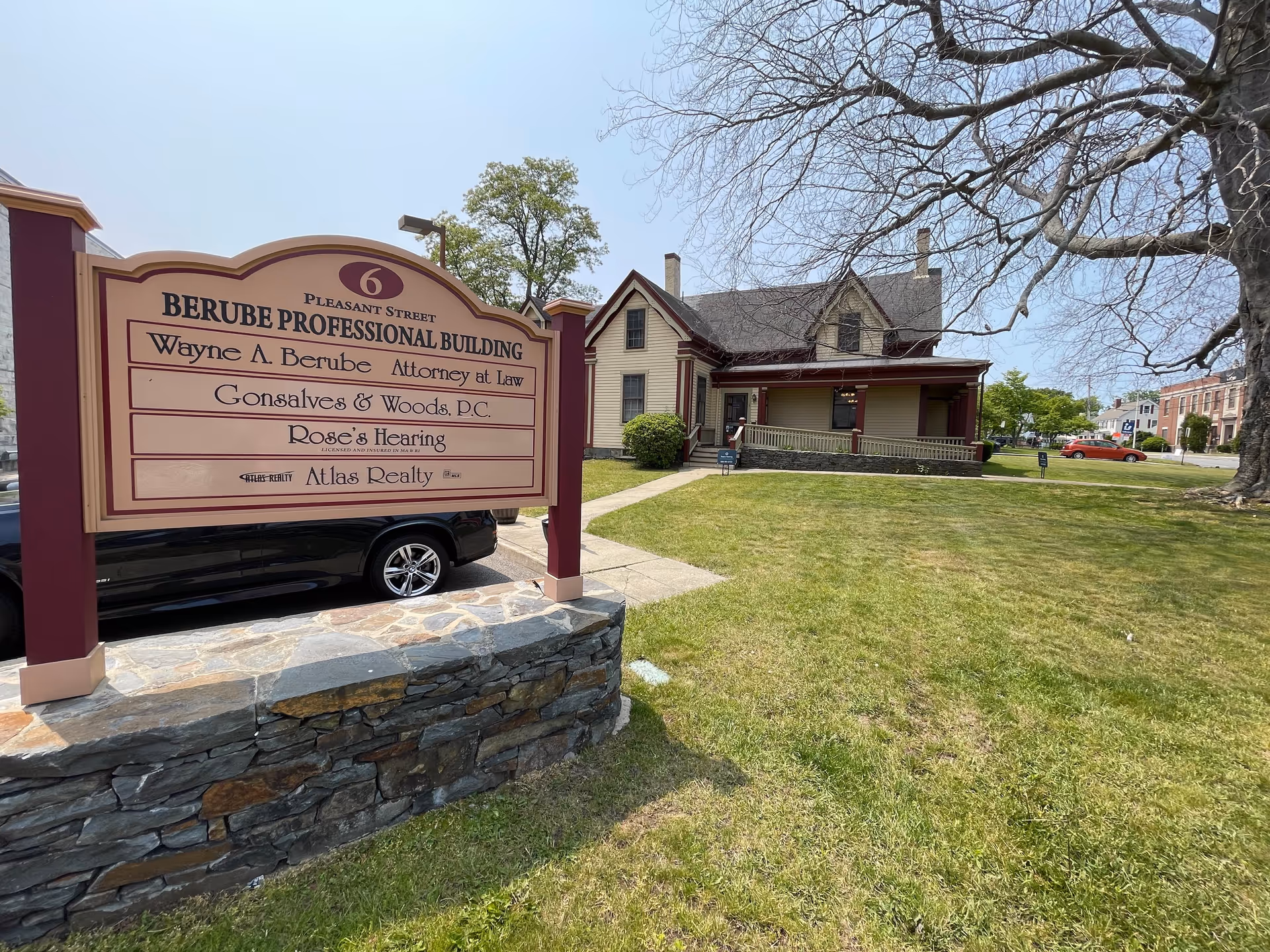Sign for Berube Professional Building in front of a brown house-style office on a grassy lawn.