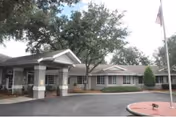 Single-story senior care facility exterior with a covered entrance and flagpole.