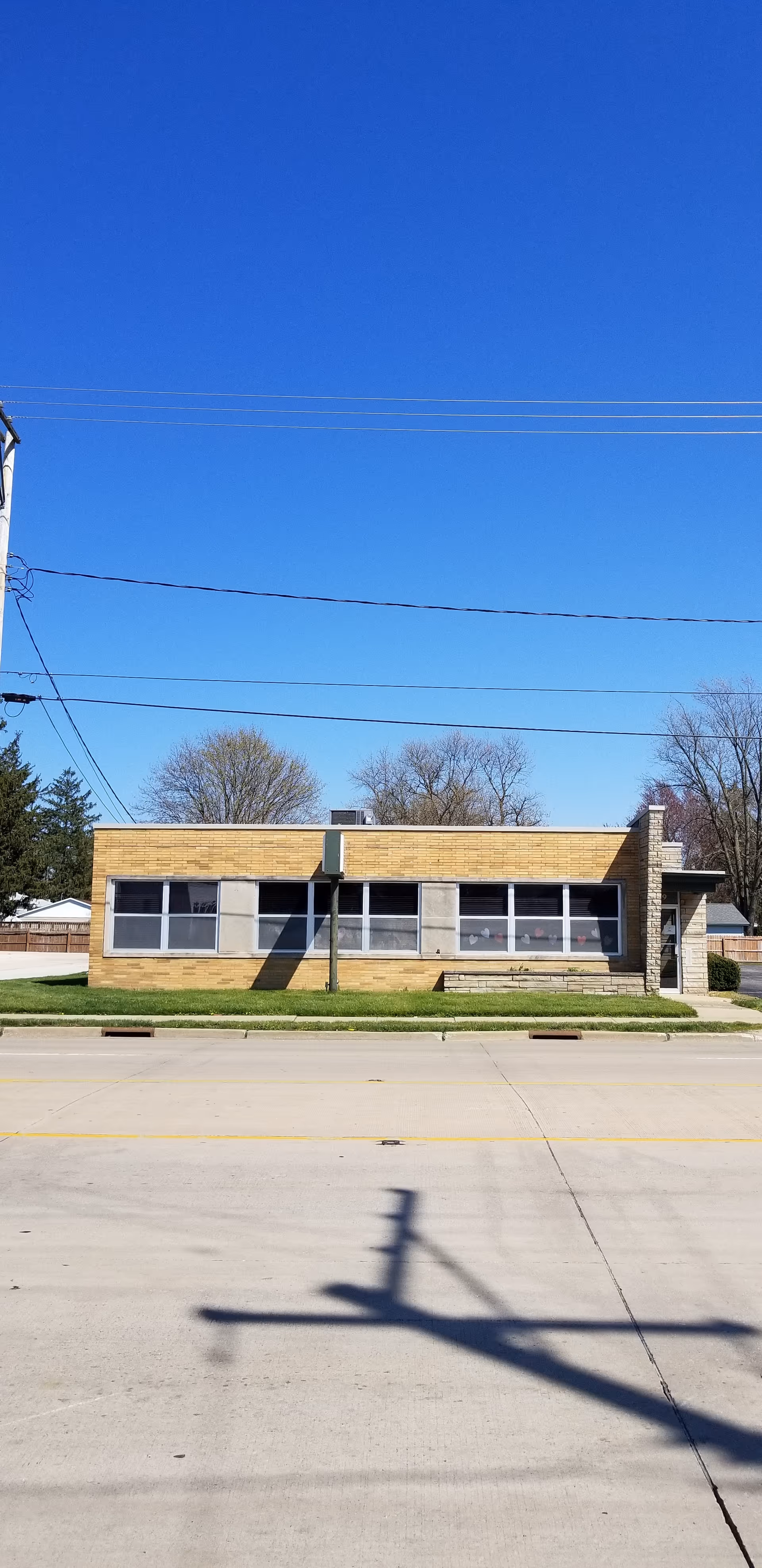 A single-story brick building with large windows on a sunny street.
