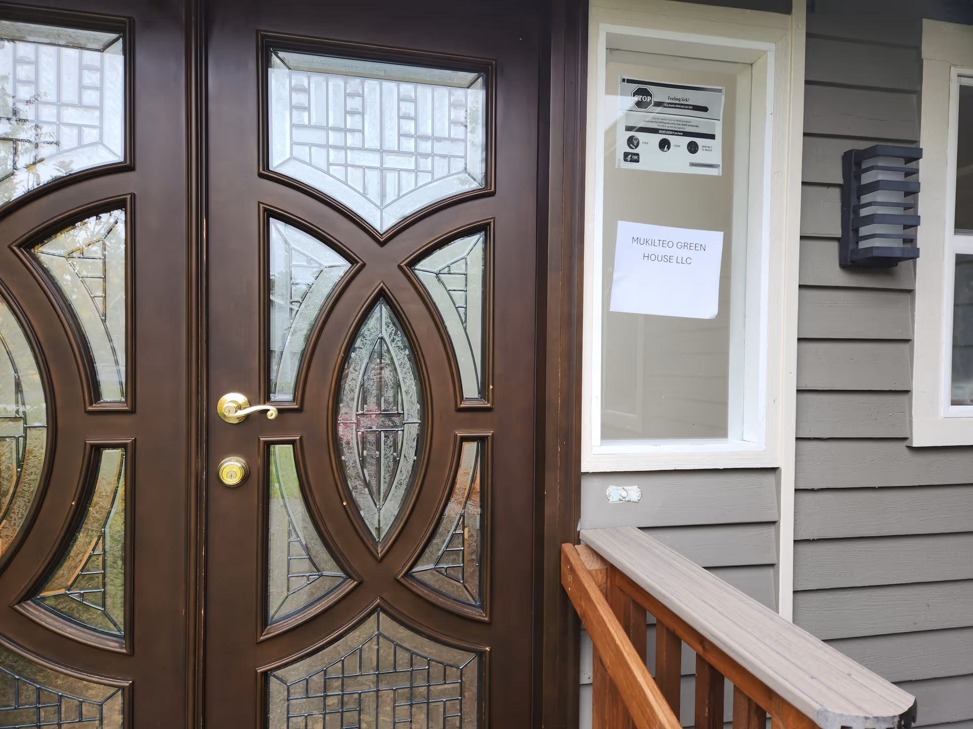 Front exterior of a gray building with decorative glass double doors and a sign.