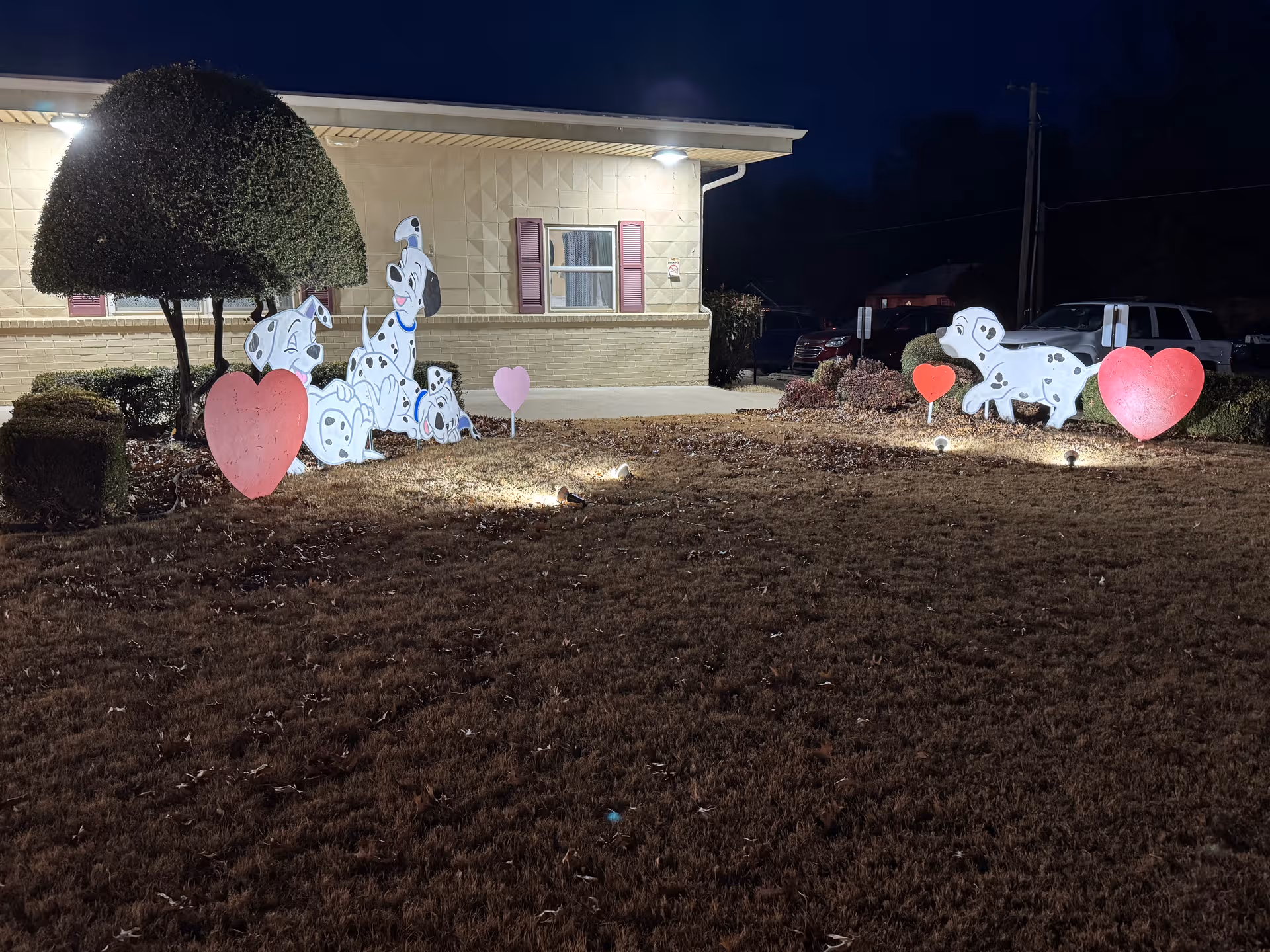 Night exterior of Cedarcrest Care Center with heart and dog-shaped lawn decorations.