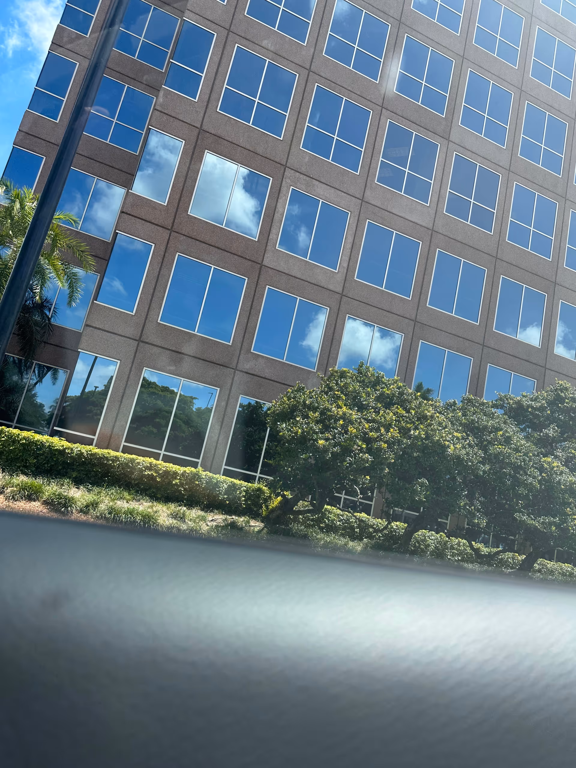 Angle view of a glass-windowed, multi-story building facade with blue reflections.