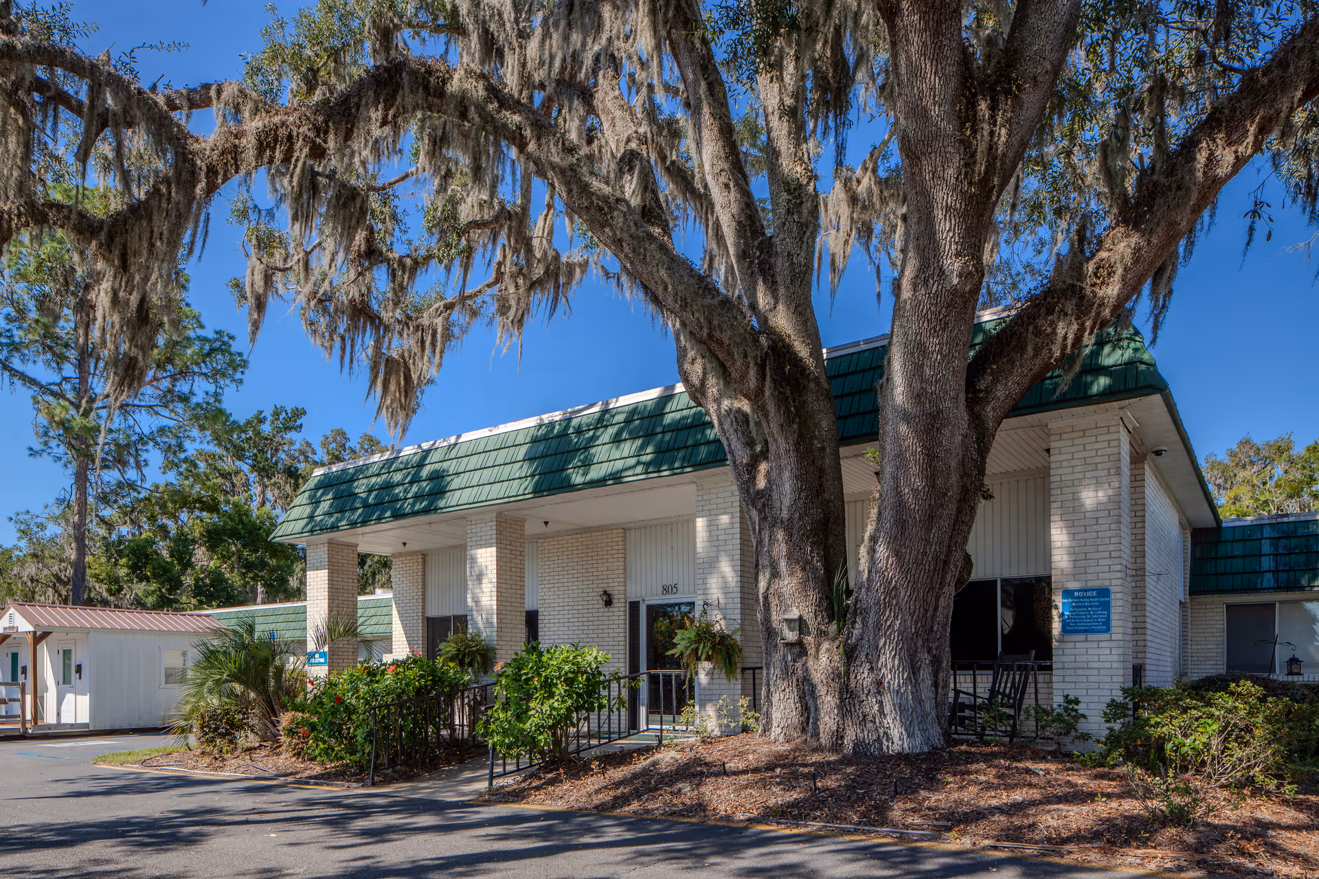 Exterior view of a PruittHealth facility with a large tree in front.