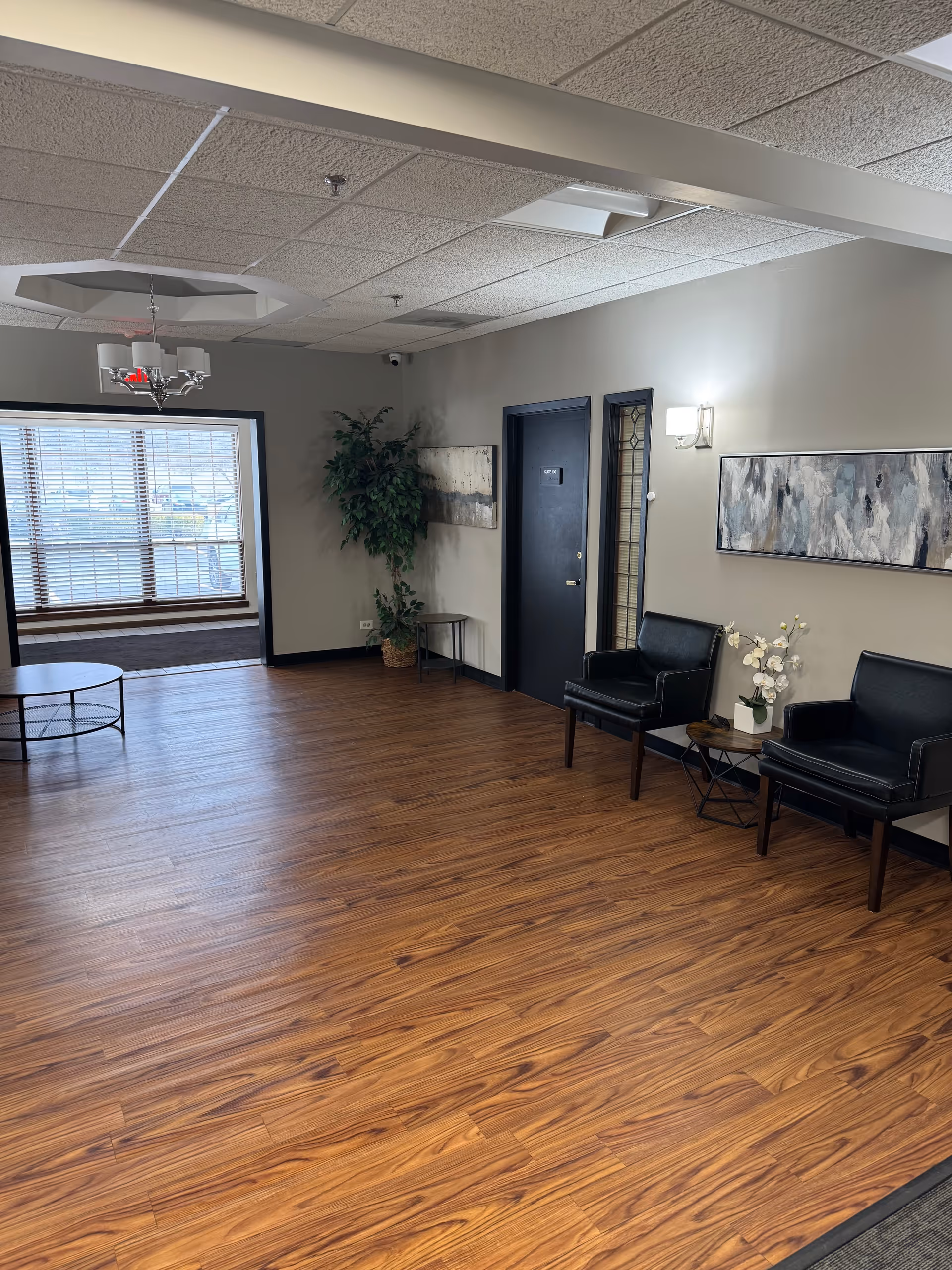 Interior senior living lobby with wood floors, seating, plant, and artwork.