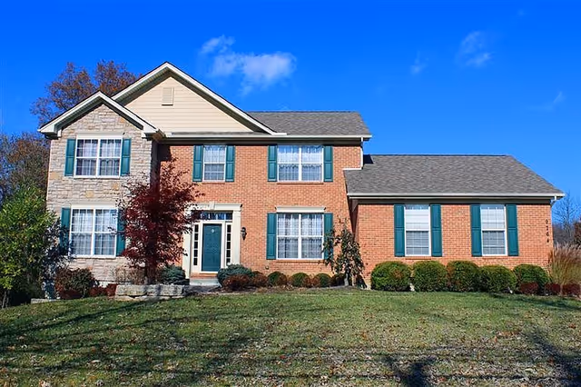 Two-story brick senior living building with green shutters and a manicured front lawn.