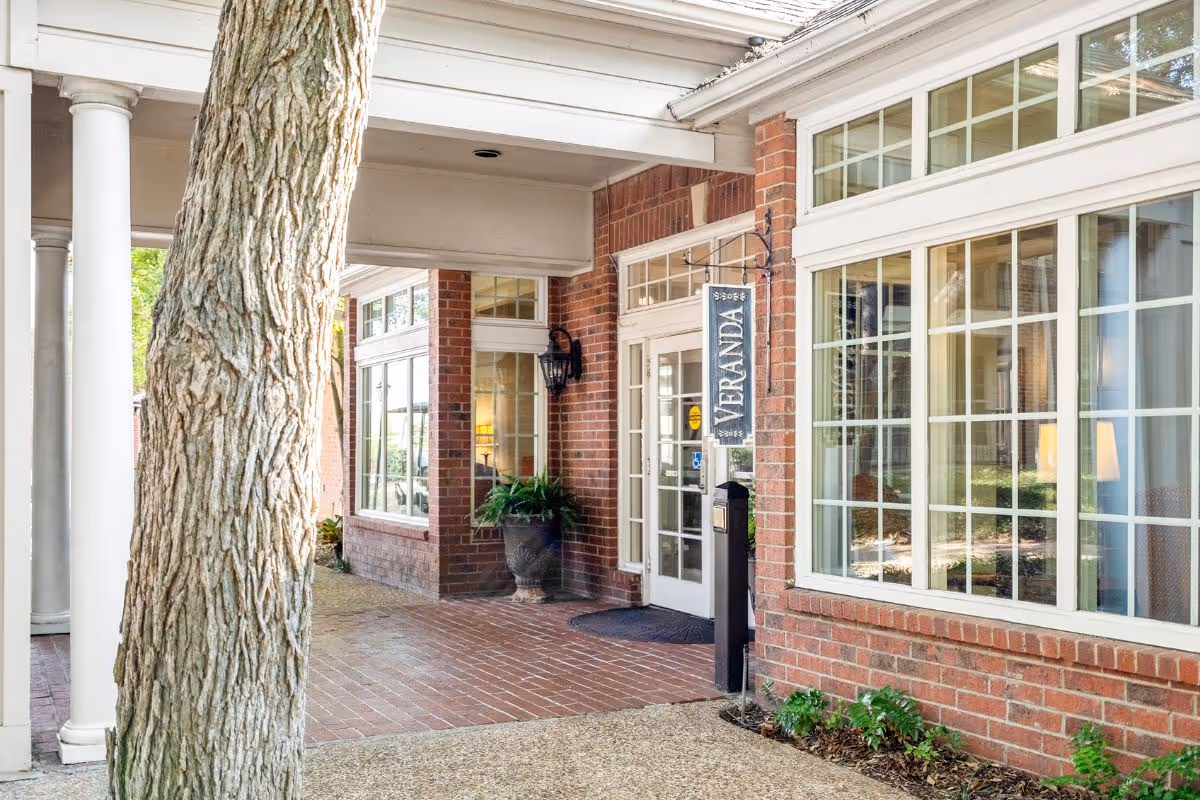 Exterior entrance of Preston Place with brick facade, large windows, and a Veranda sign.
