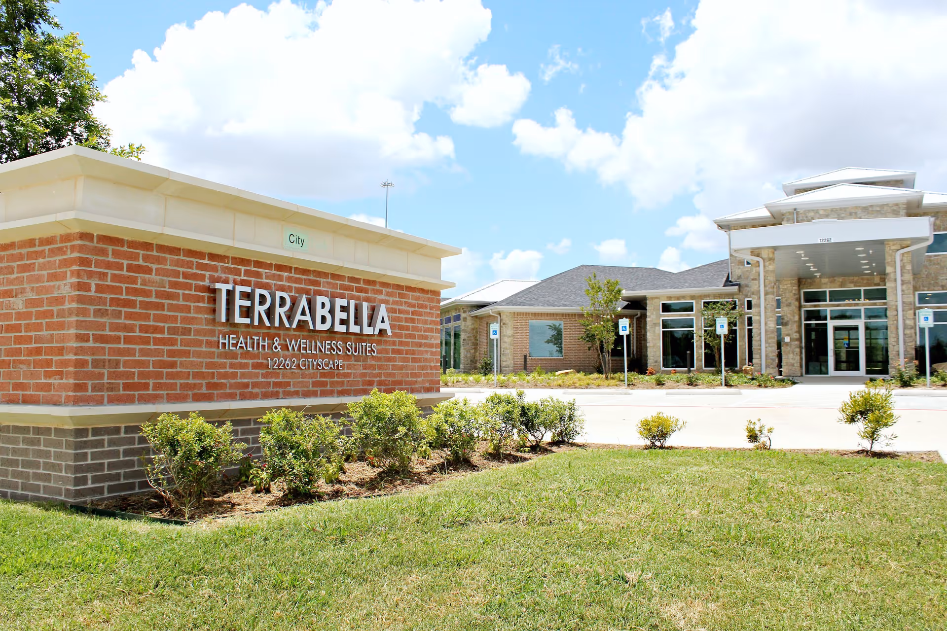 Exterior view of Terra Bella Health & Wellness Suites building with sign and landscaping.