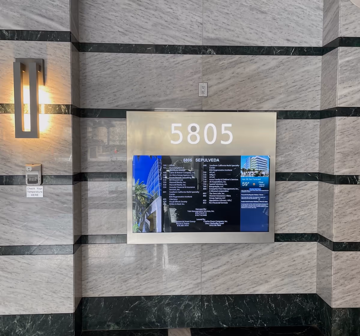 Marble interior wall with a large 5805 directory plaque and wall light.