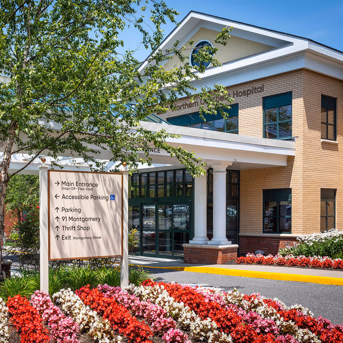 Exterior view of a medical practice entrance with sign and vibrant flowers.